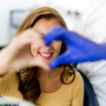 Hands making heart in front of smiling dental patient