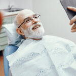 An image of an older man sitting in a dentist chair and smiling.